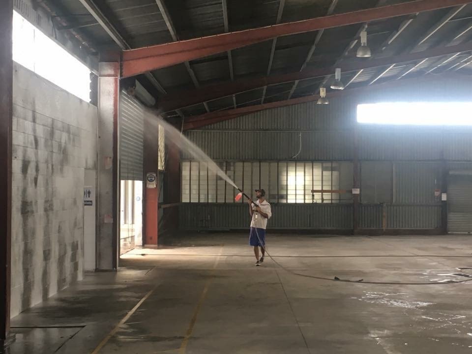 Man pressure cleaning an industrial warehouse