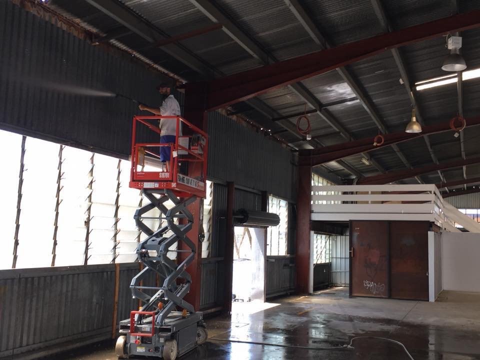 Man pressure cleaning in an industrial warehouse