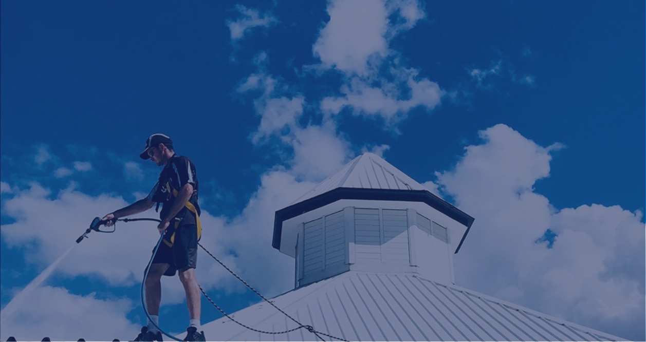 A house washing professional on the roof of a Brisbane home